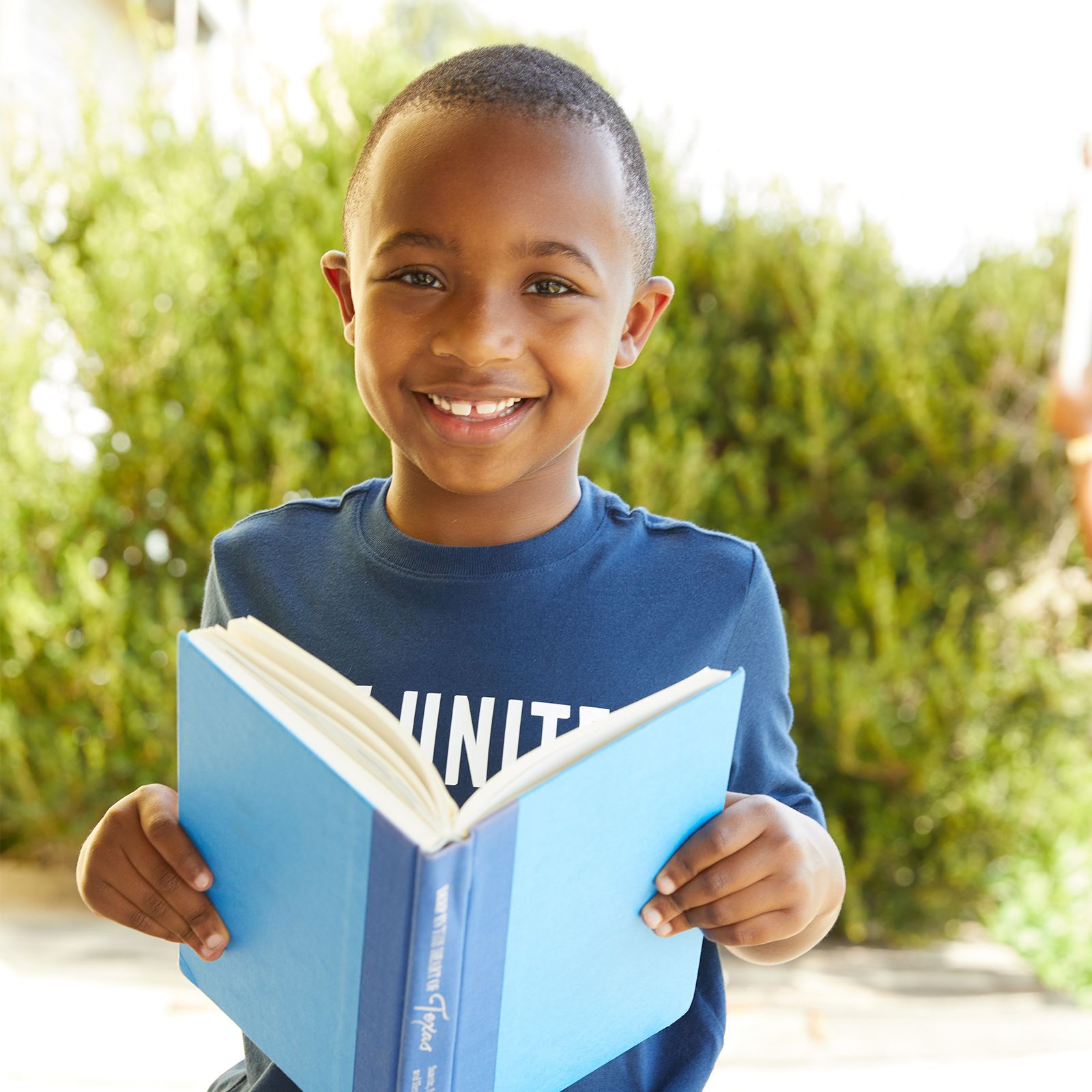 young boy with book in his hands, smiling