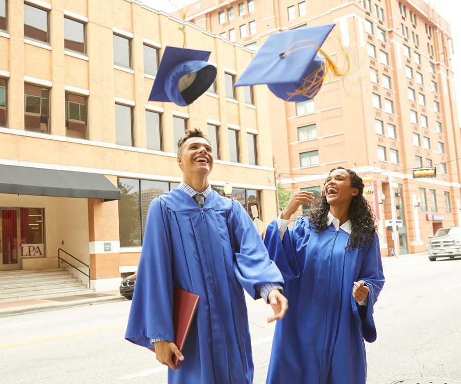 two graduates toss hats in the air