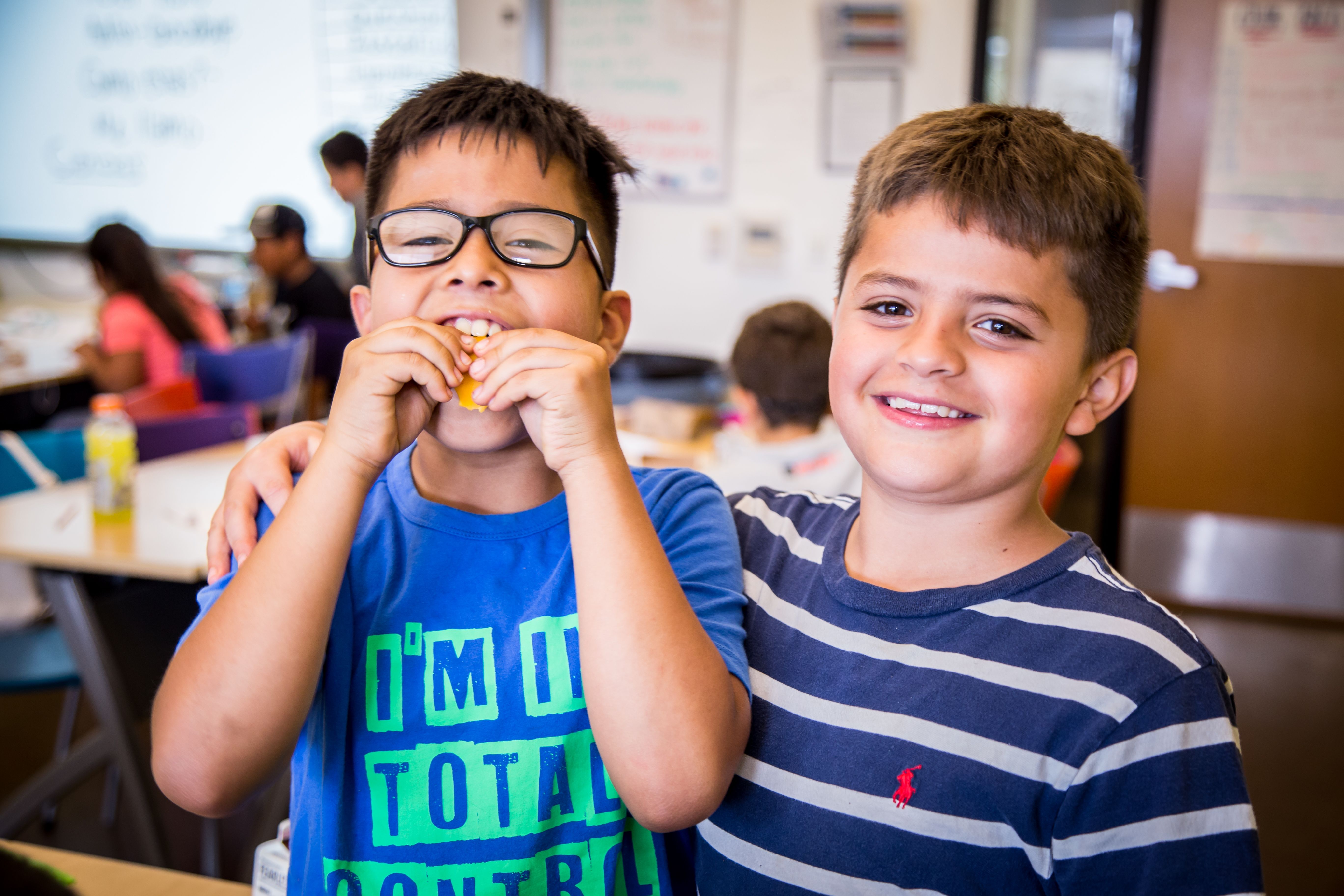 two boys, one with food in his mouth, posing