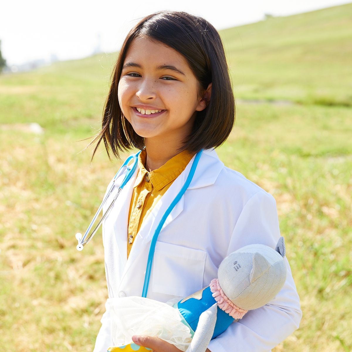 girl in doctor's jacket holds stuffed toy with tutu