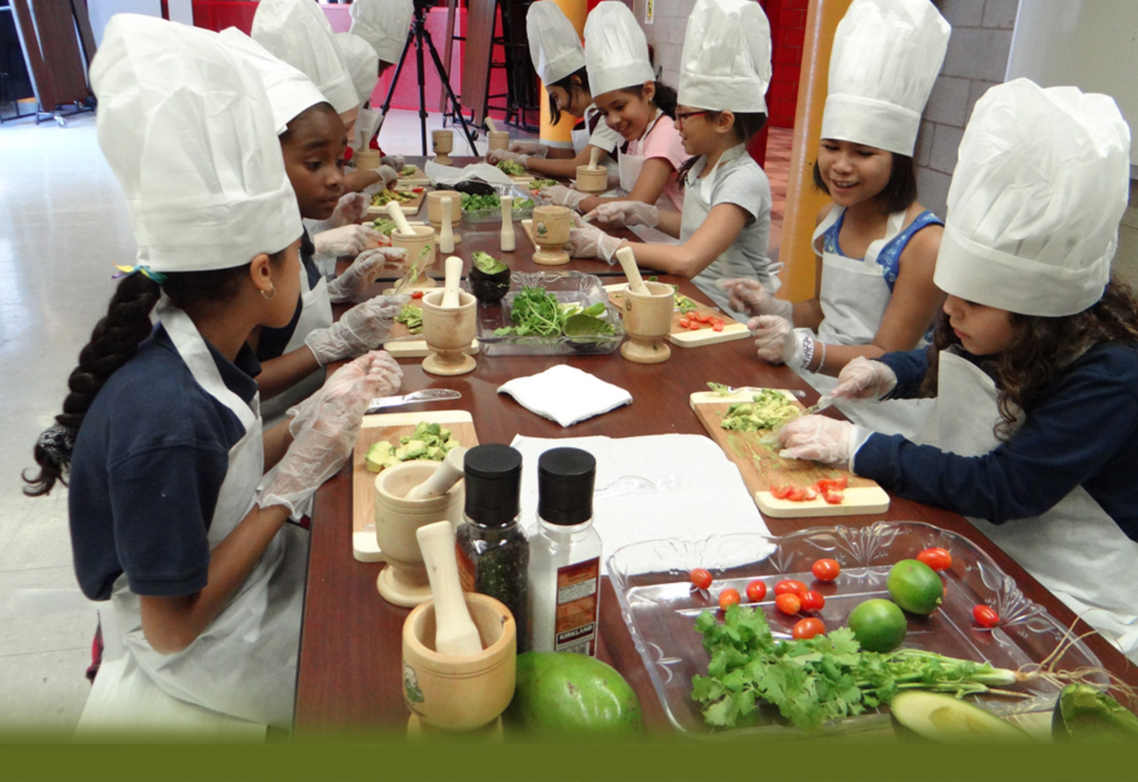 diverse group of children in chefs hats prepping food
