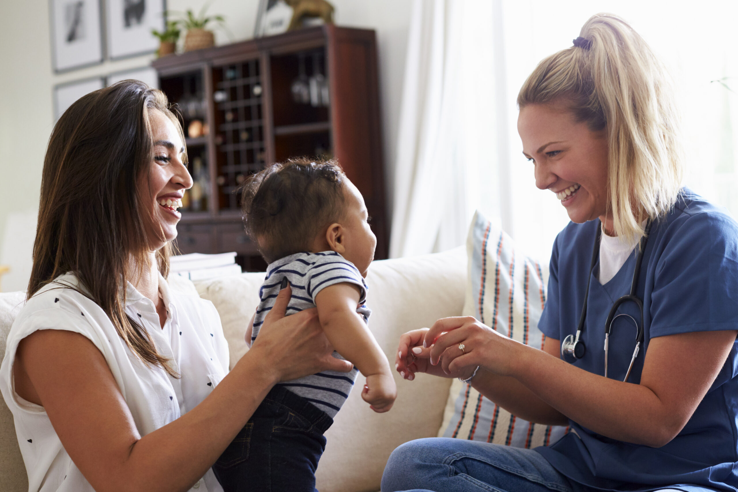 mom holding her son up while female healthcare worker checks on him