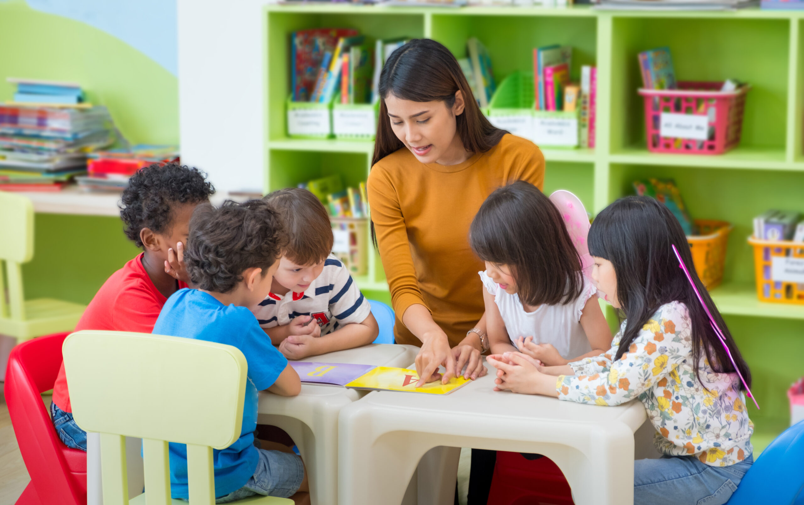female teacher reading an ABC book to preschool aged children