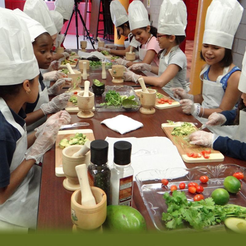 diverse group of children in chefs hats prepping food